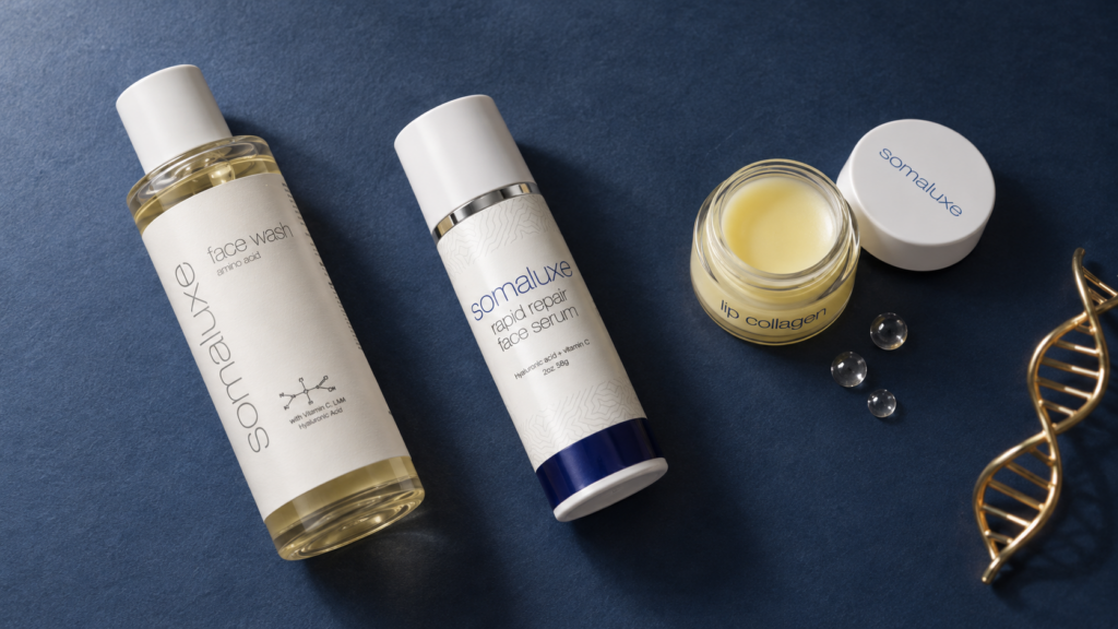 Somaluxe face wash, rapid repair serum and open lip collagen arranged on a navy surface with a gold helix